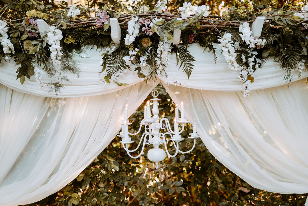 Arbor with chandelier and thick theatre curtains donned with greenery