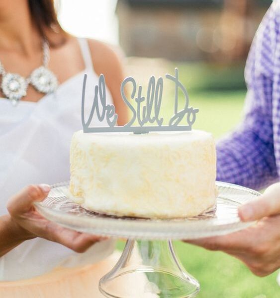 'we still do' cake topper on top of wedding cake on crystal cake stand