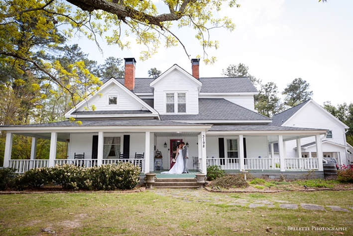 White farmhouse with a bride and groom on the porch