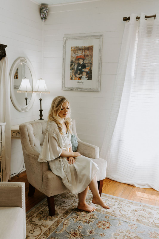 bride in vintage robe sitting on cream-colored chair