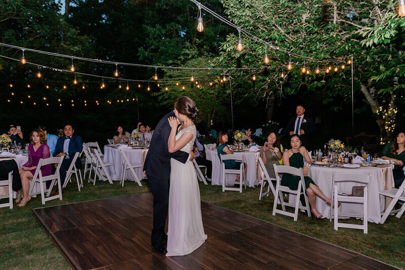 bride and groom's first dance on outside dance floor under string lights