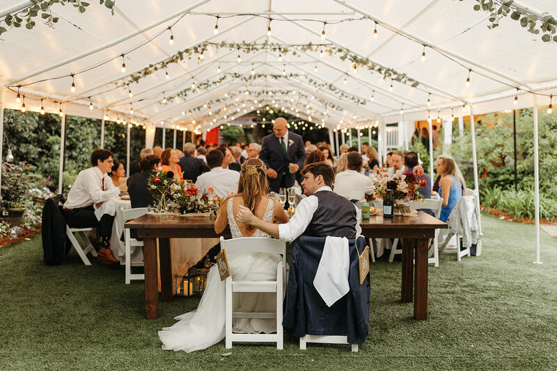 reception under tents with bistro lights and greenery