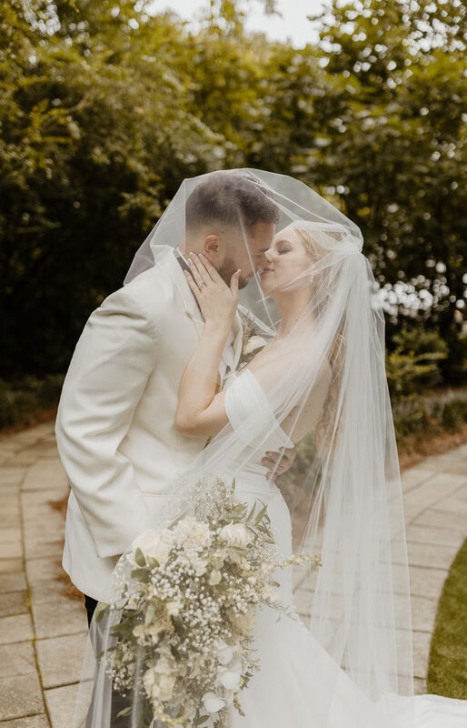 bride and groom posing under veil