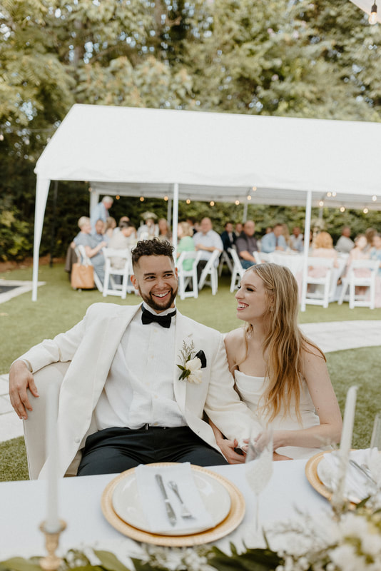 bride and groom sitting on loveseat at tented reception