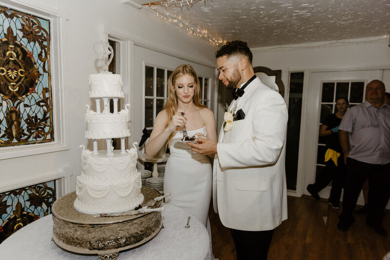 bride and groom eating slice of 4-tier vintage style cake