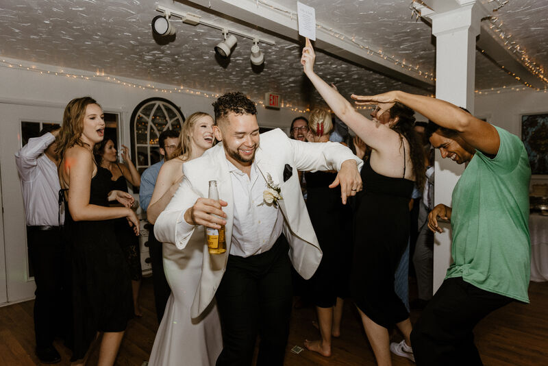 bride and groom dancing with guests at indoor ballroom