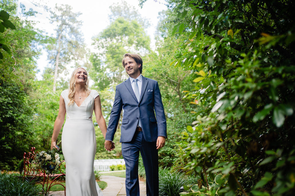 bride and groom walking hand-in-hand through garden