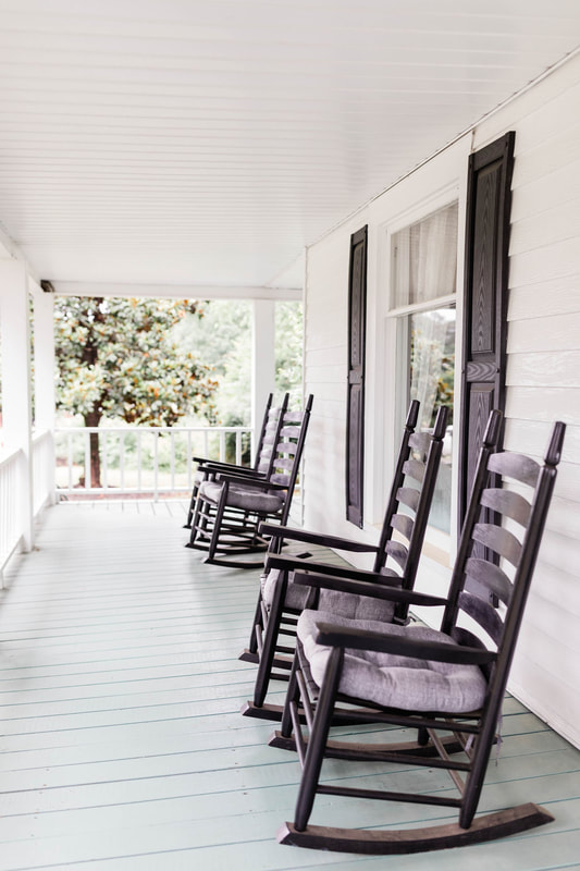 white farmhouse front porch with black rocking chairs