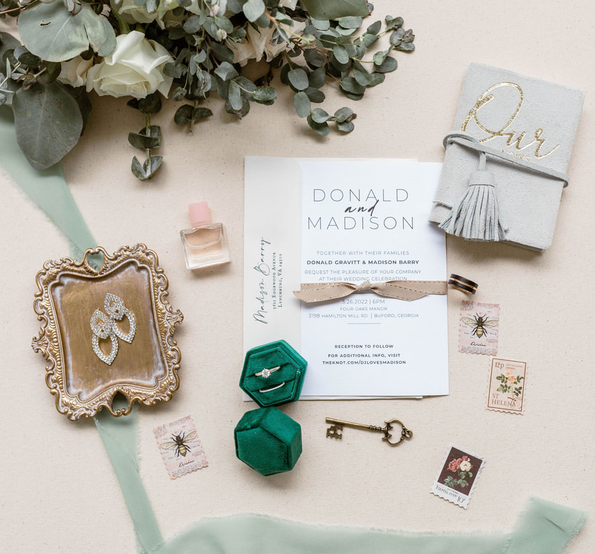 sage green wedding details with ring box, vow books, stamps, accessories, and wedding invitation