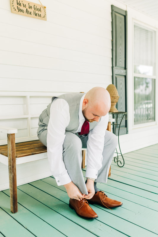 groom in grey suit sitting on farmhouse bench