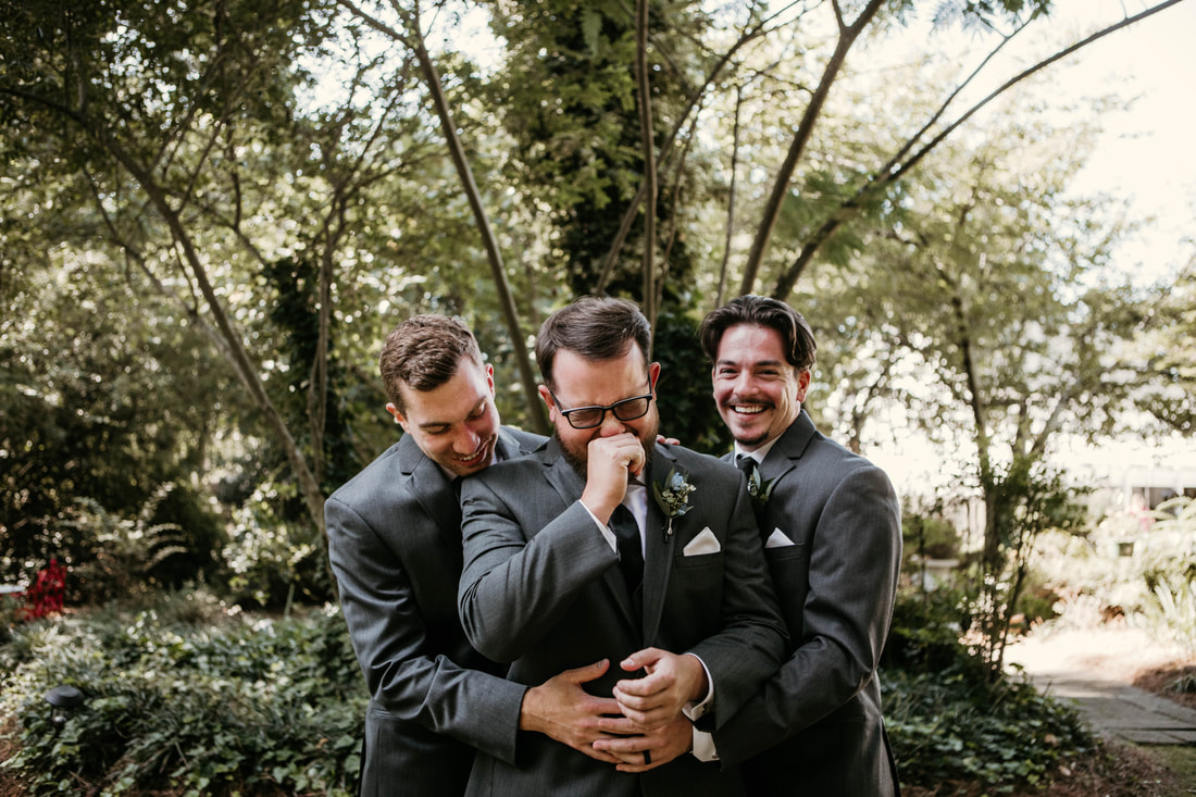 groomsmen hugging laughing groom