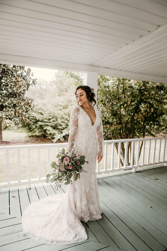 bride in lace boho dress standing on farmhouse porch