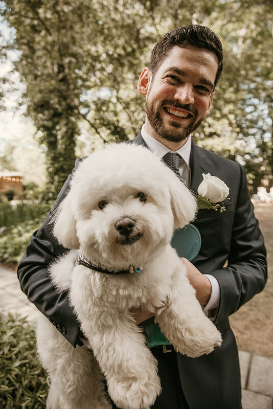 groom holding white fluffy dog