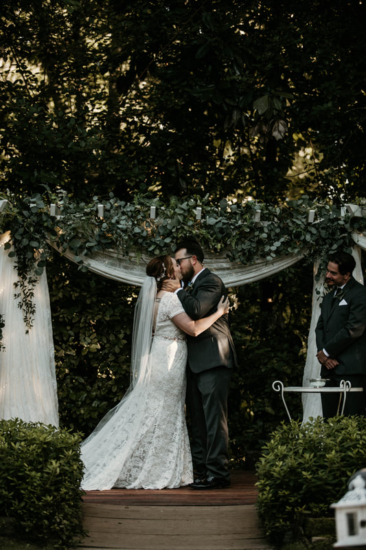 couple kisses at altar decorated with eucalyptus greenery