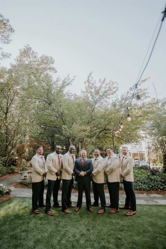 groomsmen in tan jackets standing with groom in charcoal suit