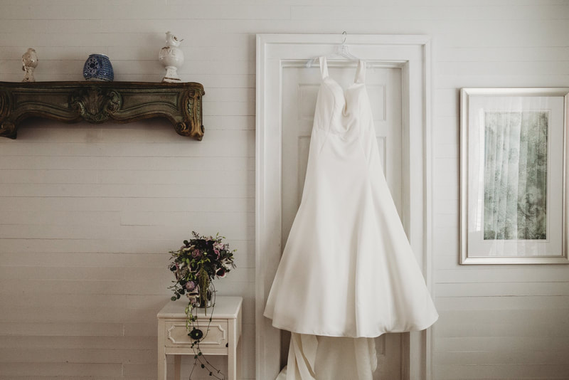 Bride's dress hanging by all-white farmhouse door