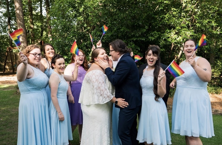 gay wedding with guests waving pride flags
