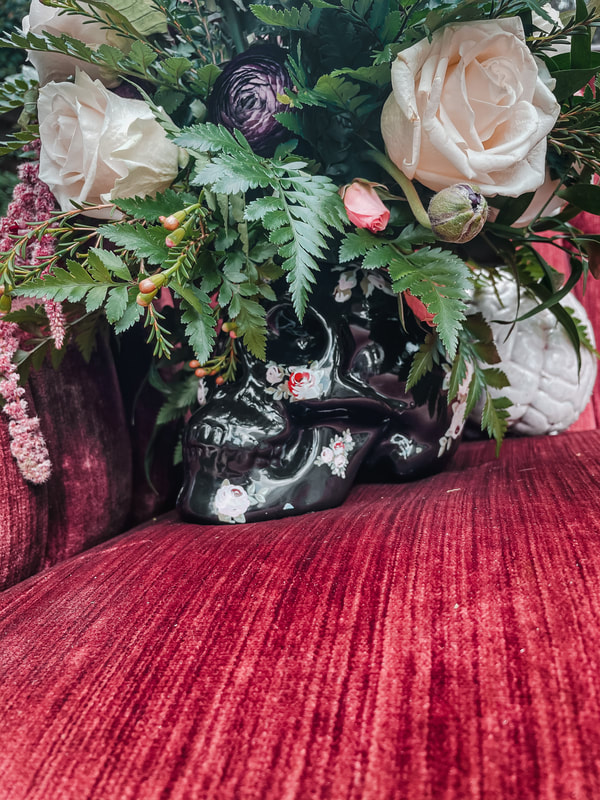 skull floral arrangement on velvet burgundy couch