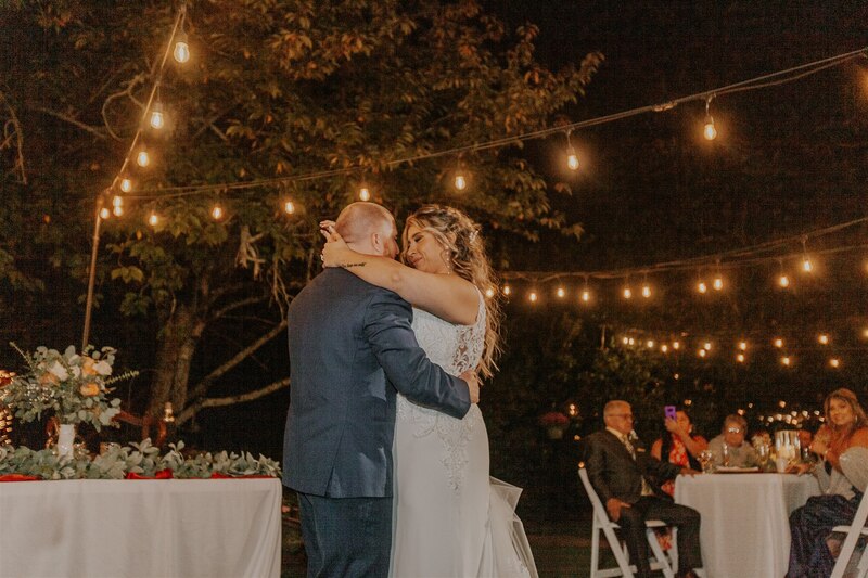 bride and groom dancing under bistro lights in garden
