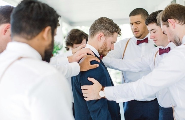 groomsmen praying over groom before wedding ceremony