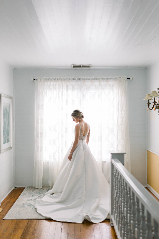 bride posing in wedding dress with light from window shining through