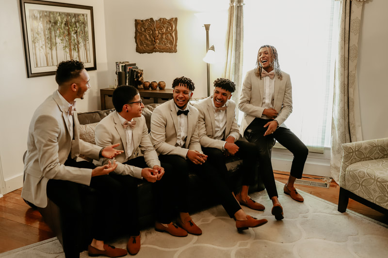 groom and groomsmen wearing champagne-colored sports coats sitting in farmhouse groom's room