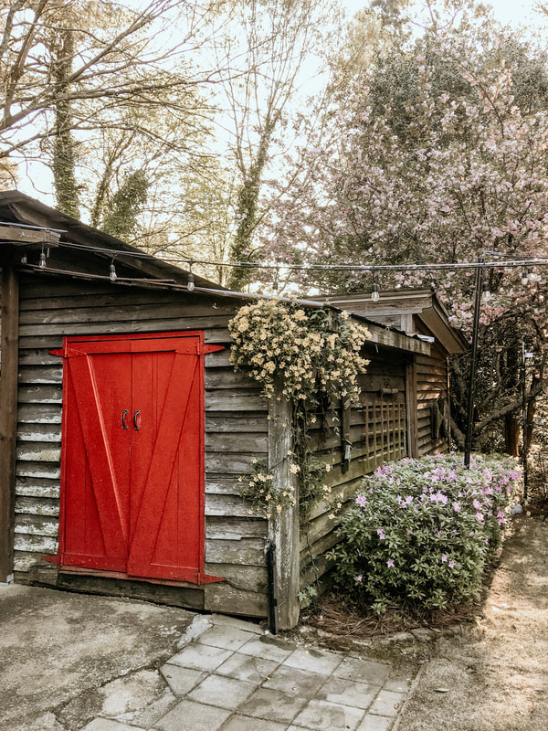 Four Oaks' red doors on the smoke house with flowers hanging along top