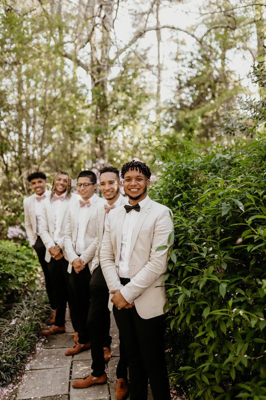 The groom and groomsmen wait for the ceremony to start on a side path off the ceremony area.