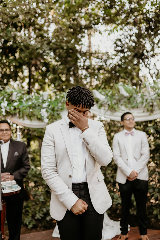 The groom wipes his eyes after seeing his bride start walking down the aisle.