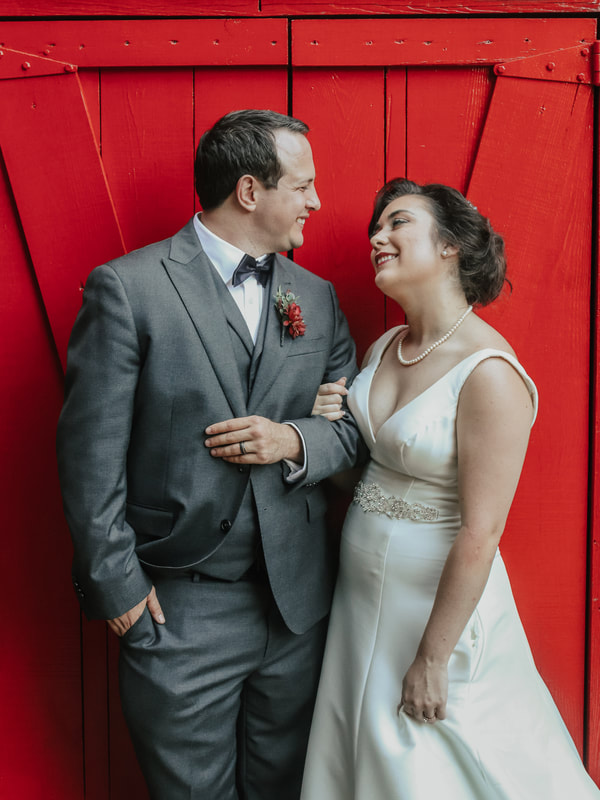 vintage bride and groom smiling by red barn doors