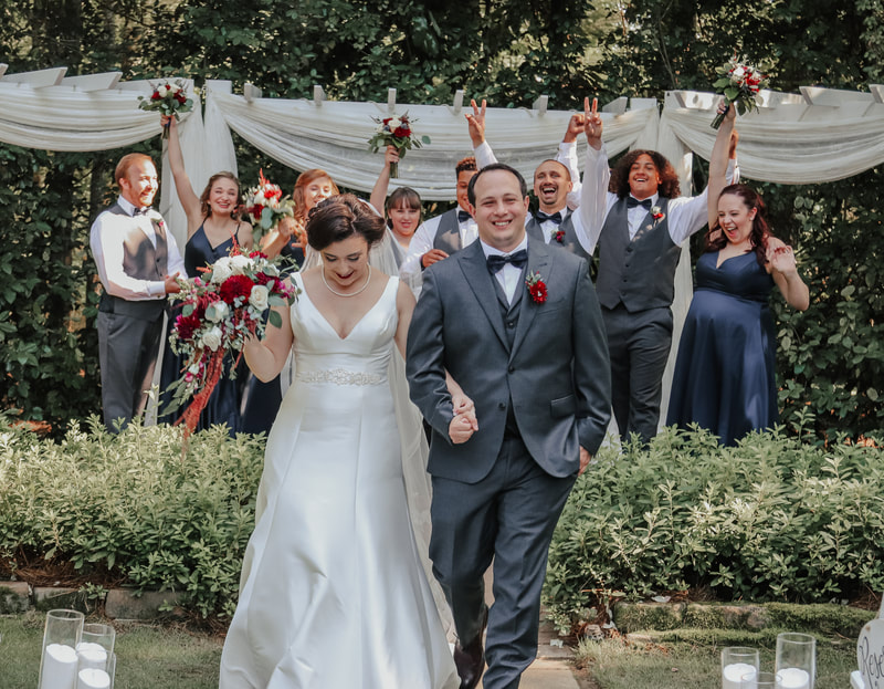 wedding party cheers as bride and groom walk from altar