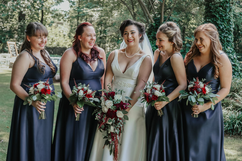 bridesmaids in navy dresses with burgundy and white bouquets