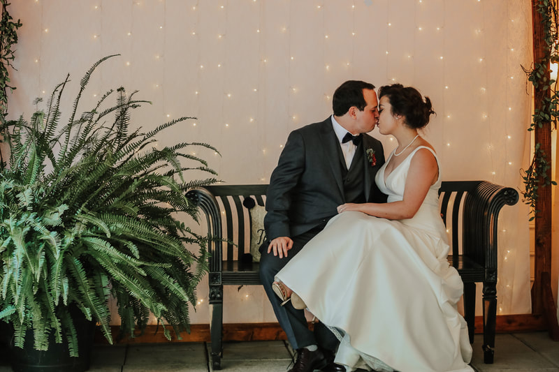 newlyweds kiss on black bench