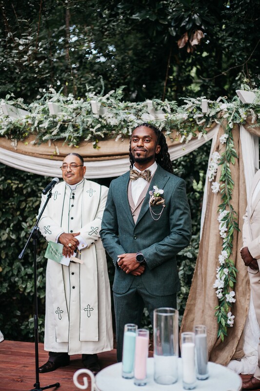 groom in olive suit by outdoor altar