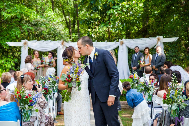 newlyweds kissing in aisle of bright spring ceremony 