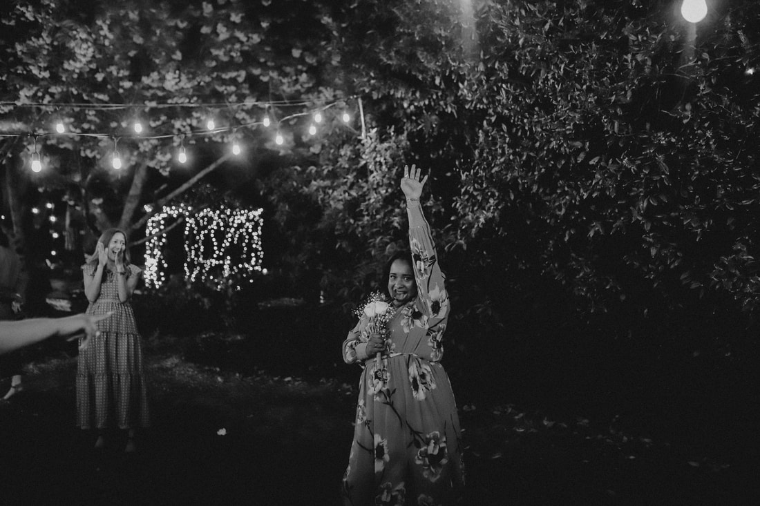 The victor of the bouquet toss takes a celebratory photo in black and white.