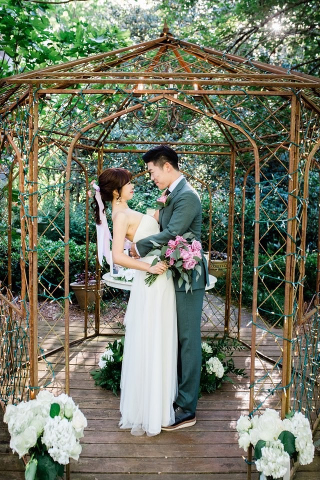 couple facing each other in gazebo surrounded by lights
