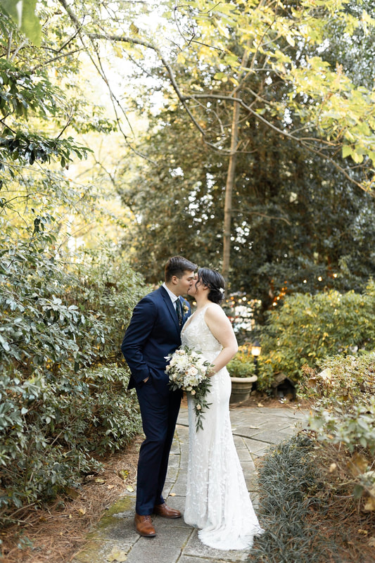groom in navy suit kissing bride with white bouquet