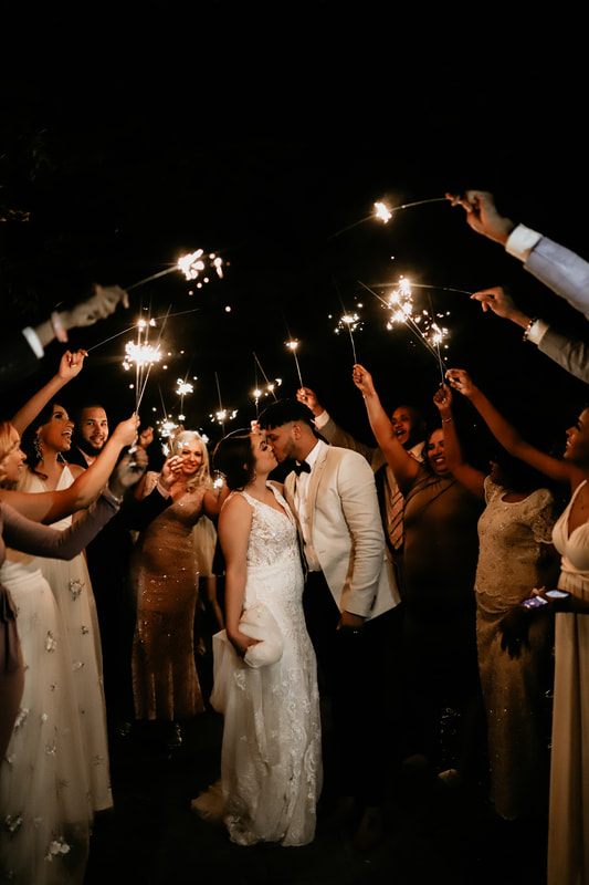 Guests hold sparklers to create a tunnel as the bride and groom kiss during their sparkler grand exit.