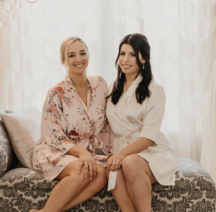 bride with maid of honor getting ready in white and floral robes
