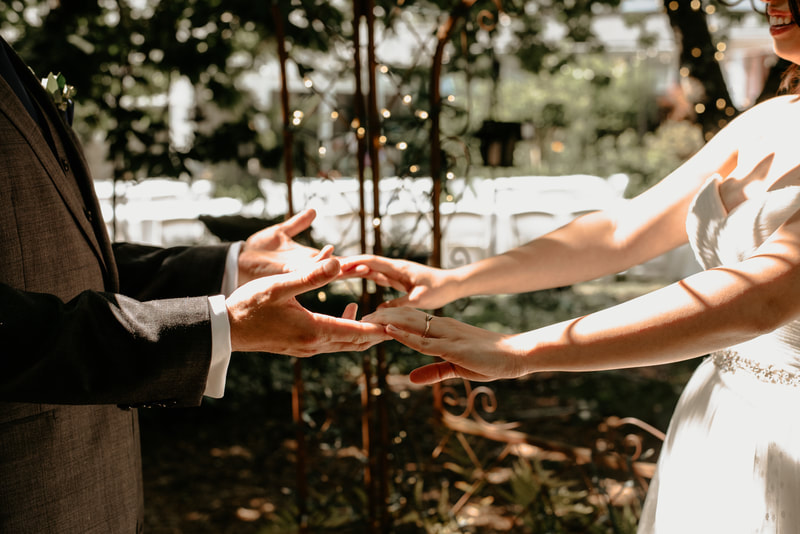 Bride and groom touching hands for pictures at an outdoor wedding.