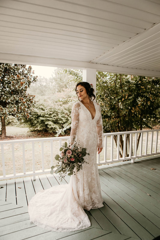 bride with boho dress posing with bouquet on farmhouse front porch