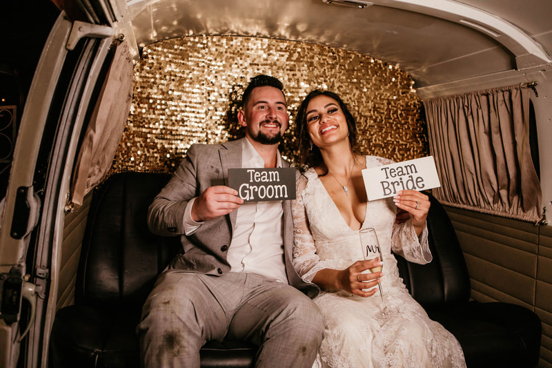 couple holding team groom & bride signs in photobooth