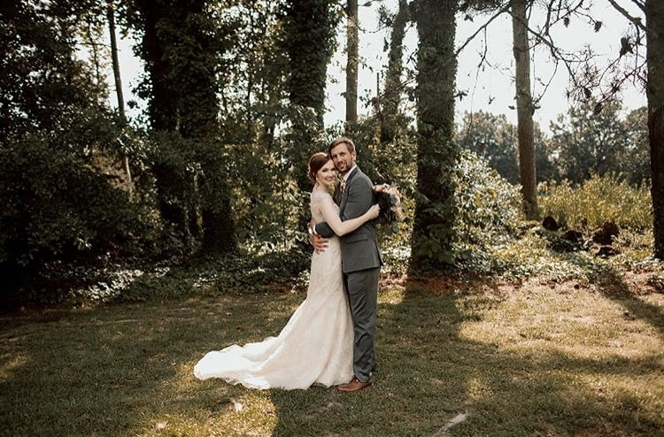 Newlyweds hug surrounded by trees outside