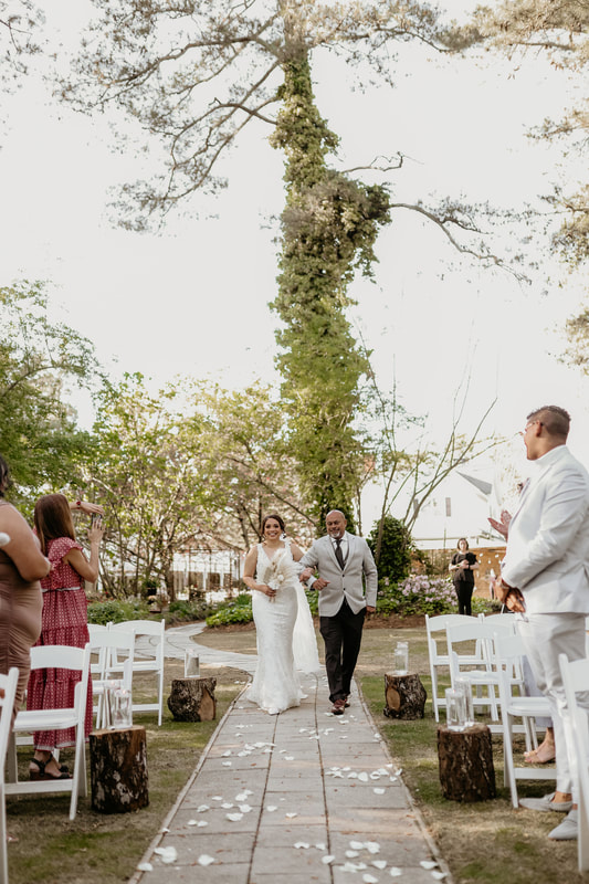 bride walking down the aisle with her dad at an outdoor wedding venue