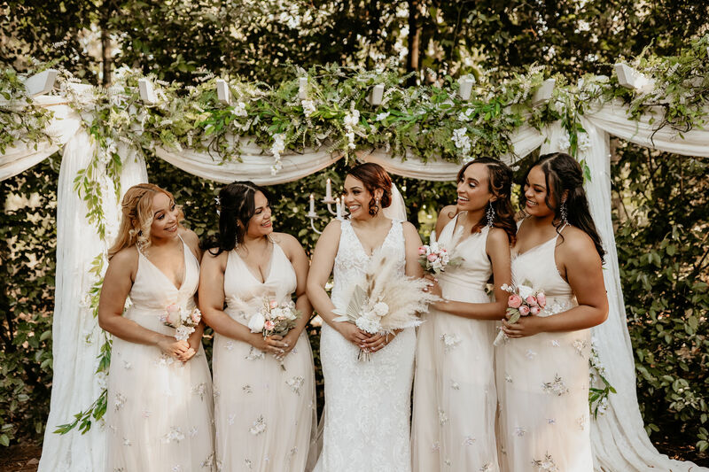 bridesmaids and bride posing for an outdoor ceremony picture