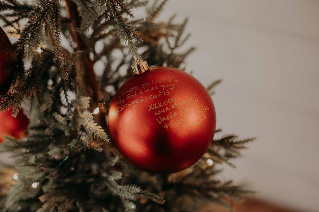red shiny ornament with messages from guests written in gold pen