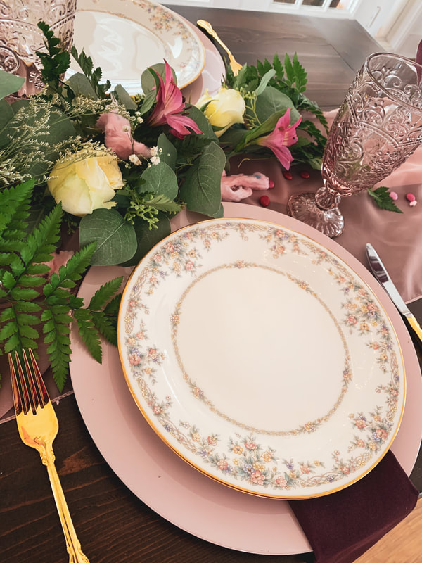 pink charger, floral china, purple napkin, and gold flatware