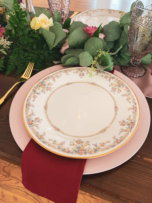 pink charger and floral china with red napkin hanging