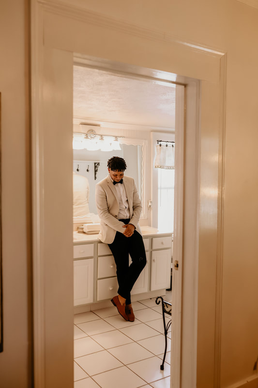 groom posing in white groom's room bathroom